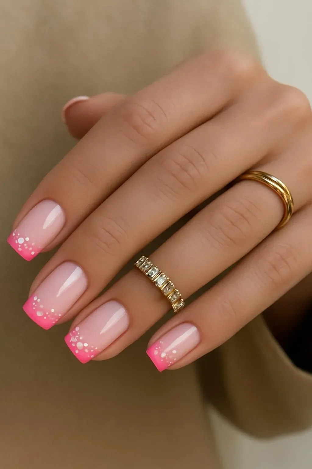 Glossy baby pink French tip nails adorned with tiny floral gems for spring 2026.