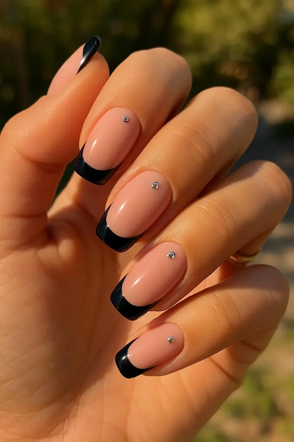 Elegant black French tip almond nails adorned with sparkling rhinestones.